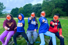 Five children pictured in a field with trees in the background, enjoying the activities. 